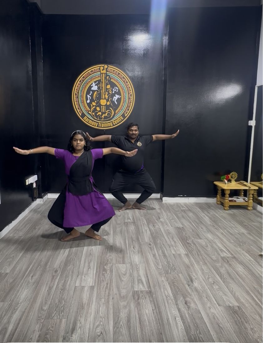 Instructor and student practicing a classical dance pose in the studio
