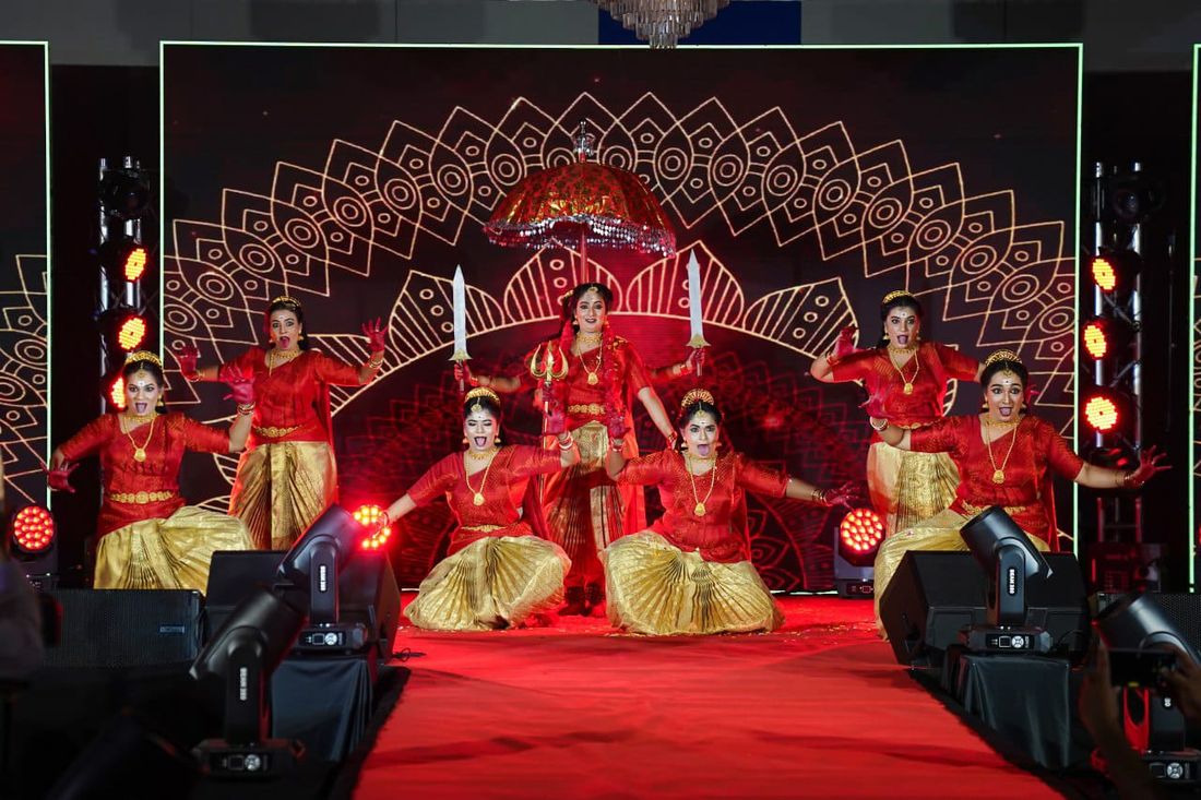 Classical dance students performing on stage in red and gold costumes